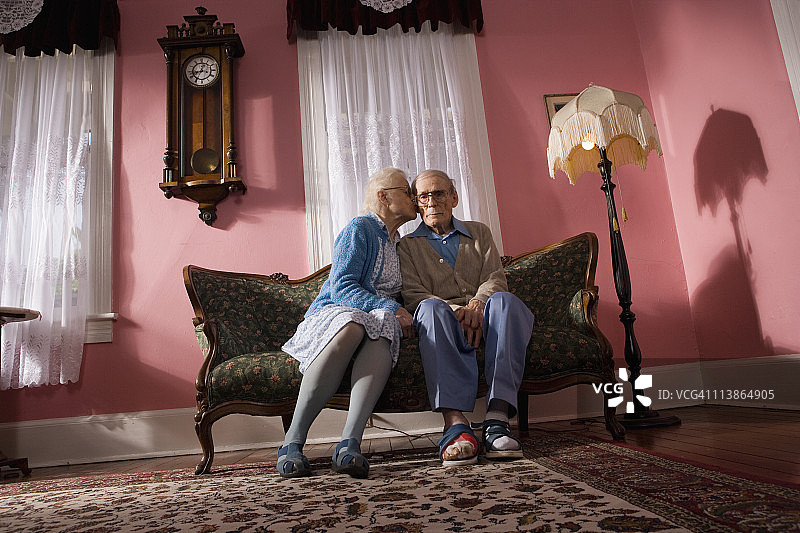 一对深情的老夫妇坐在客厅的沙发上图片素材