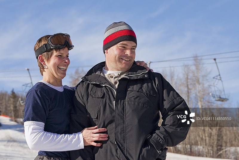 一个男人和一个女人在一起大笑，戴着无头帽和滑雪面具在一个滑雪场图片素材