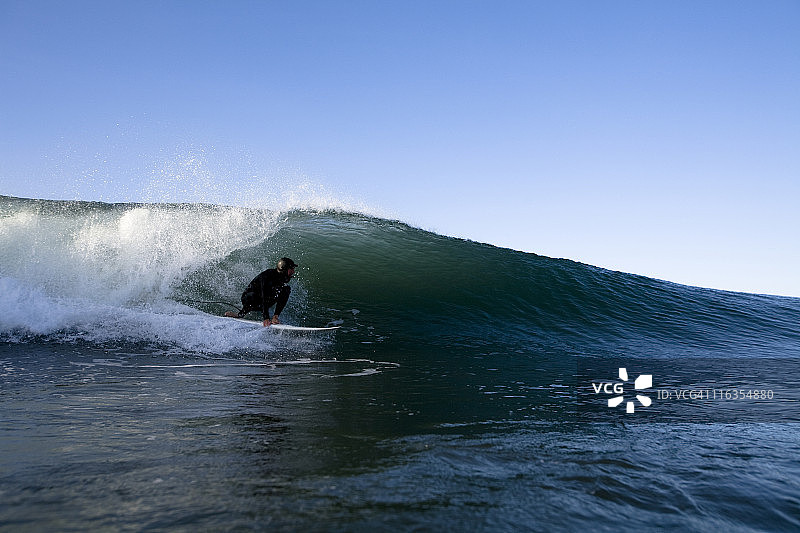 加州胡尼米港，一名戴着兜帽的冲浪者正在准备一个桶。图片素材