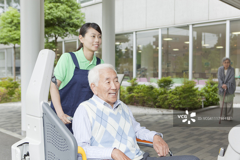 日本本州神奈川县，医疗工作者帮助一位坐轮椅的老人进入一辆面包车图片素材