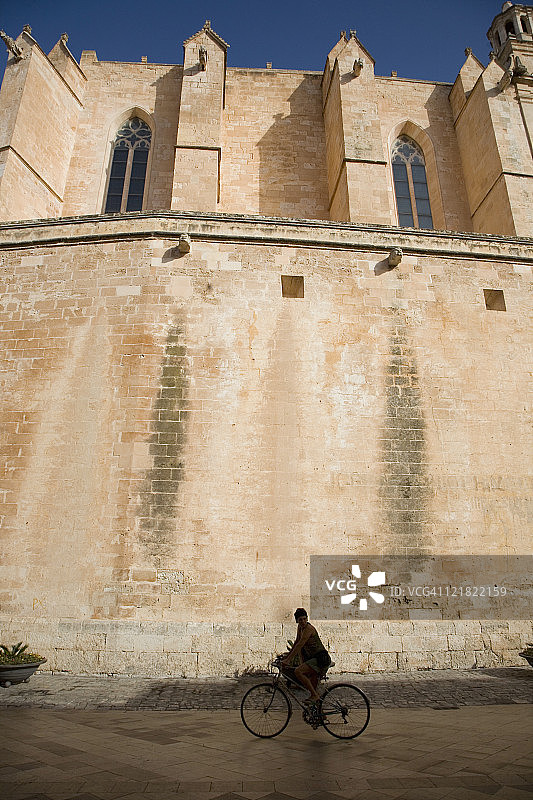 一名女子骑着自行车经过西班牙梅诺卡市Ciutadella大教堂图片素材