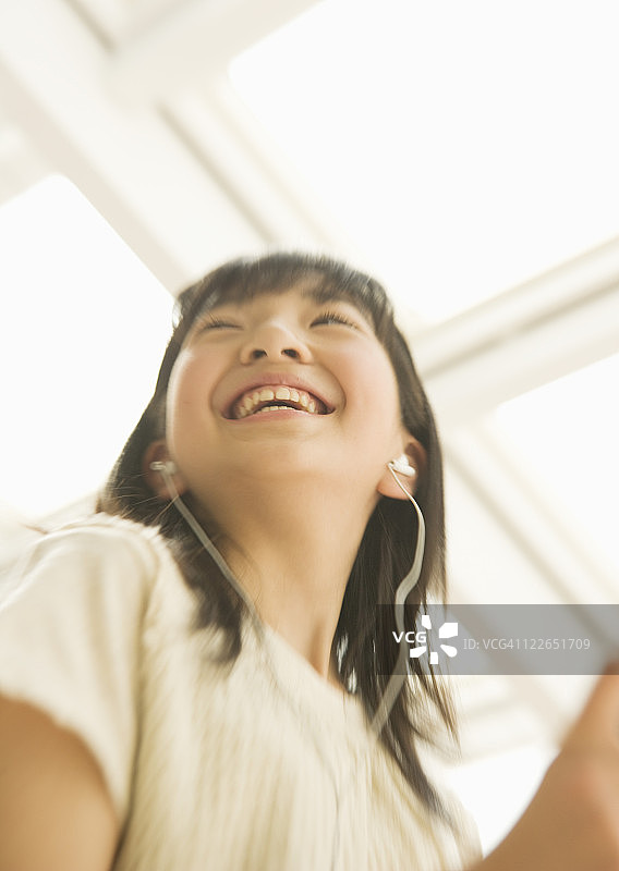 微笑的女孩用耳机听音乐图片素材