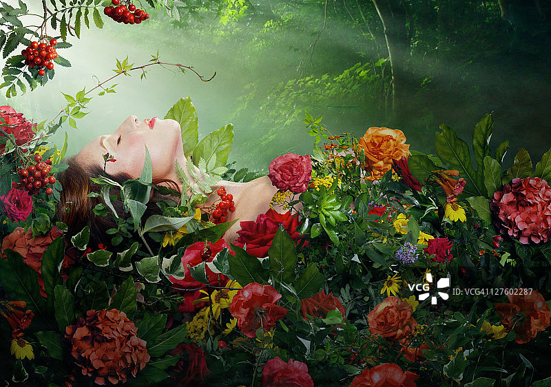 一个美丽的女人躺在红玫瑰床上图片素材