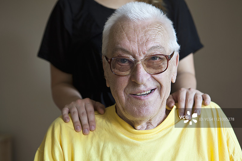 一个老人在疗养院，手放在他的肩膀上，专注于他图片素材