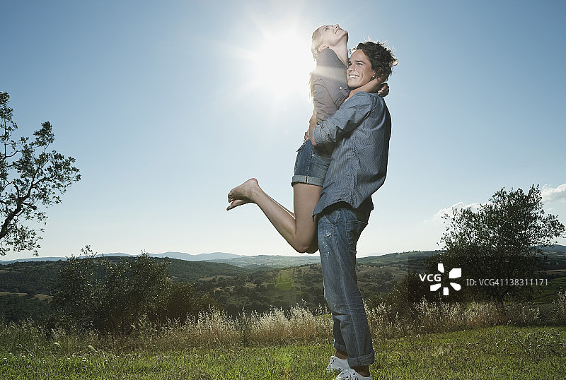 意大利，托斯卡纳，一个年轻人背着一个女人背对着太阳图片素材