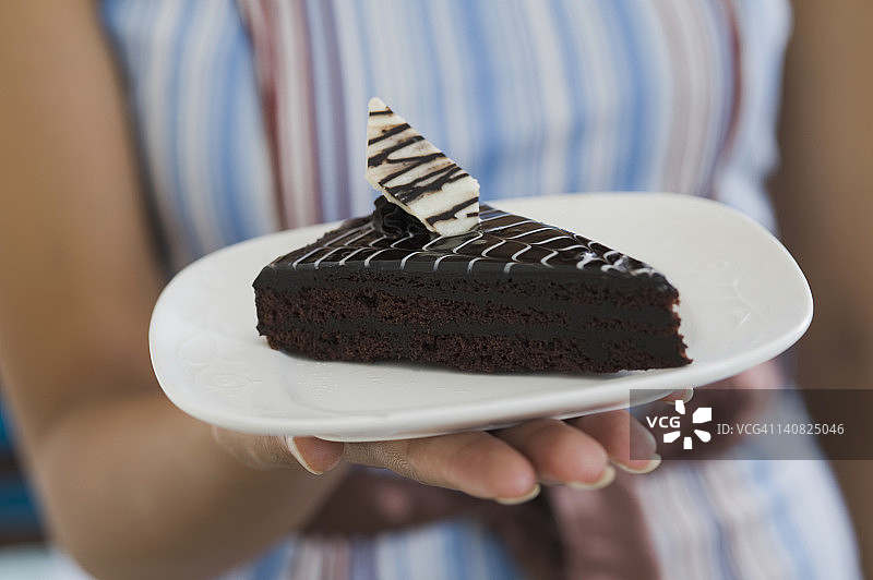 一个女人拿着一个盘子里的巧克力糕点的中段视图图片素材
