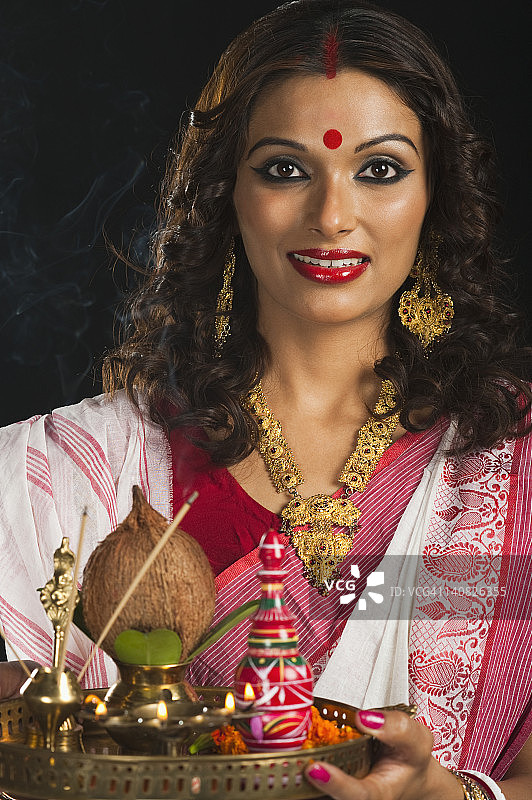 一个孟加拉女人拿着一个普贾塔利面带微笑图片素材