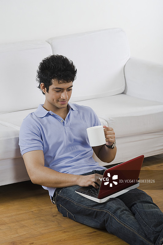 一个拿着笔记本电脑的男人，一杯咖啡掉在地上图片素材