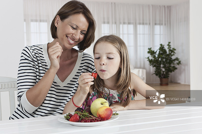 德国，慕尼黑，母女吃着水果，面带微笑图片素材