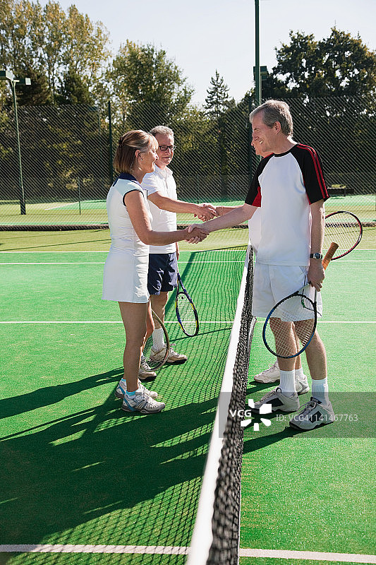 老年人和成年人在网球场上握手图片素材
