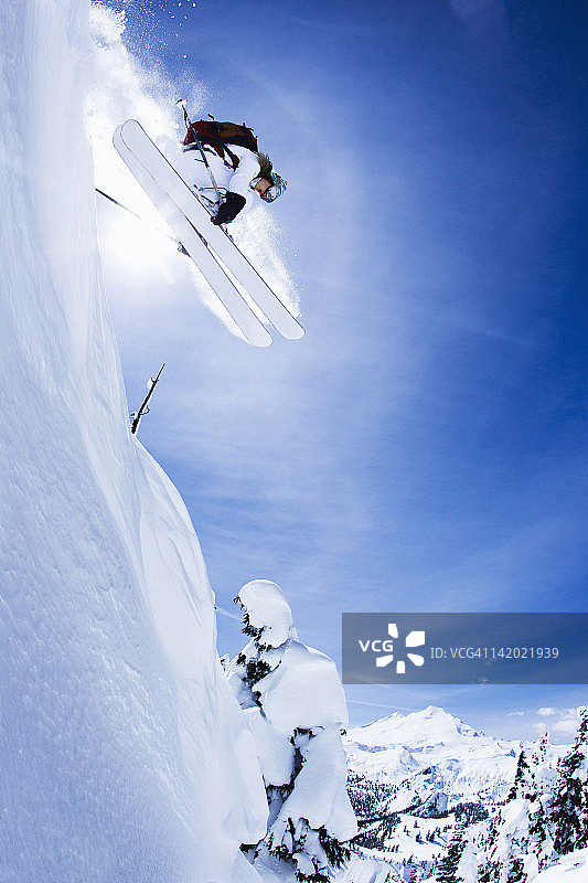 滑雪者在雪坡上跳跃图片素材