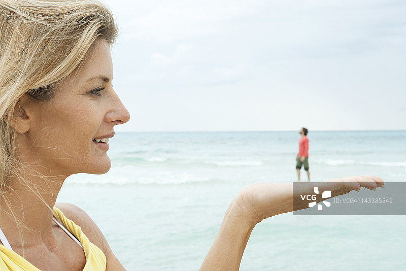 在海滩上，一个女人似乎手里握着一个小男人图片素材