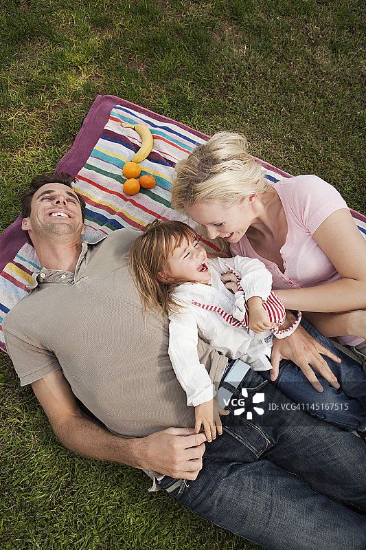 西班牙，马略卡岛，帕尔马岛，一家人躺在草地上，微笑着图片素材