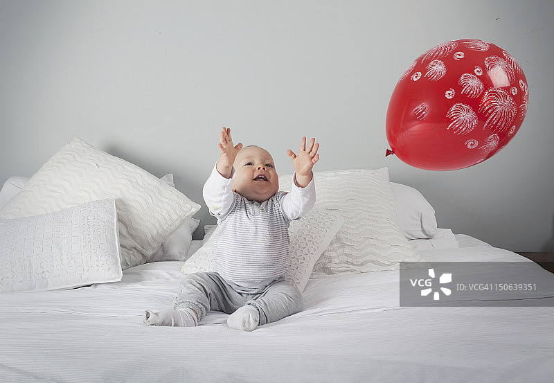 小男孩在床上玩气球图片素材