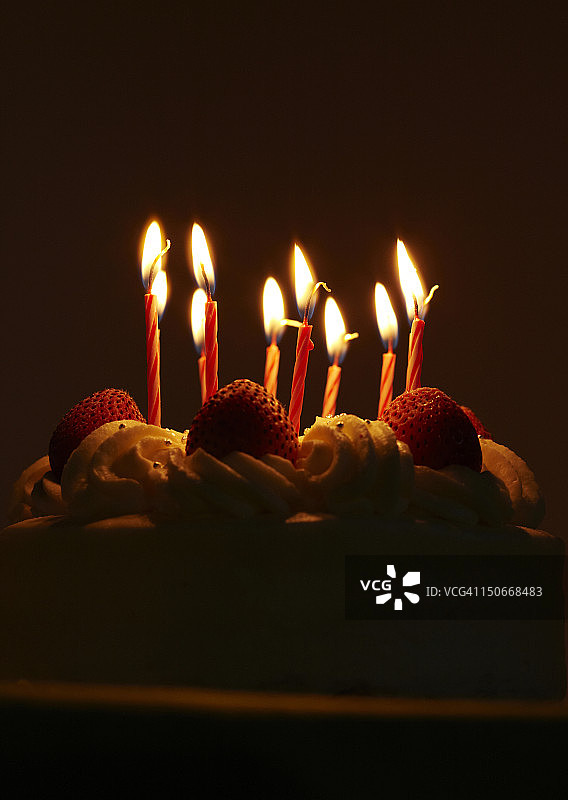 草莓生日蛋糕和点燃的蜡烛图片素材