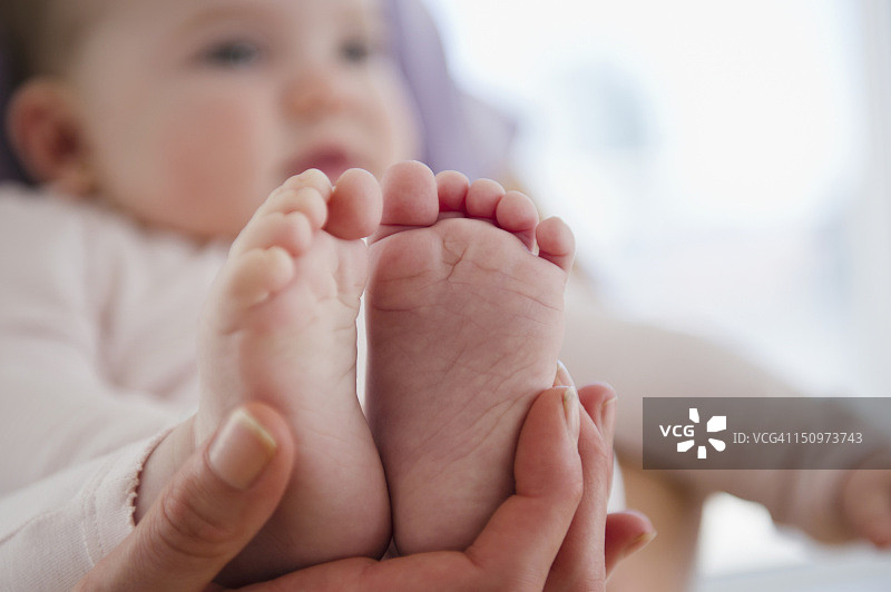 美国，新泽西州，泽西城，母亲的手抱着婴儿的女儿(6-11个月)的脚的特写图片素材