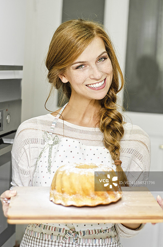 微笑的年轻女人在厨房里吃蛋糕图片素材
