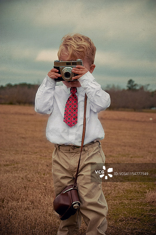 穿着犀利的蹒跚学步的小男孩拿着相机图片素材