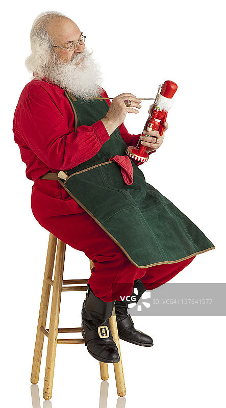 圣诞老人在白色上制作玩具。垂直的。XL图片素材