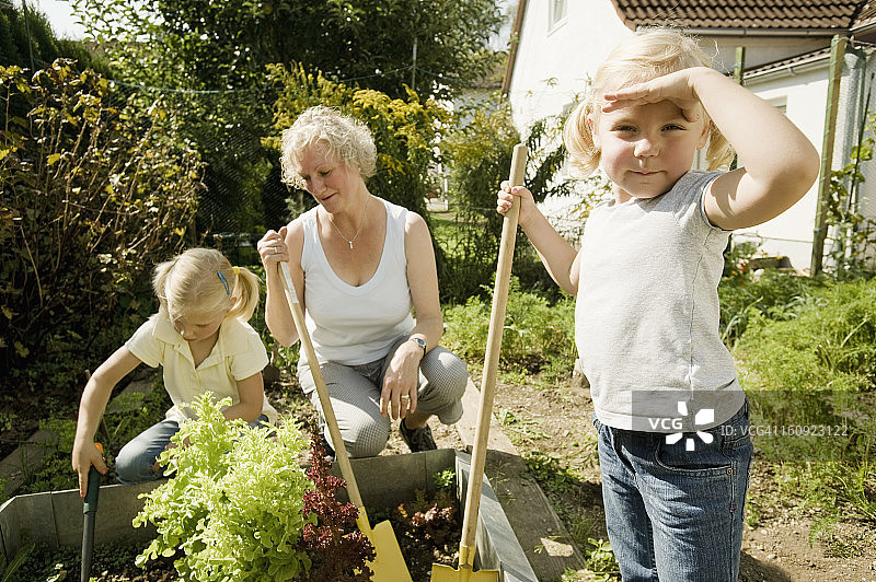 德国，巴伐利亚，祖母和孩子们在菜园里工作图片素材