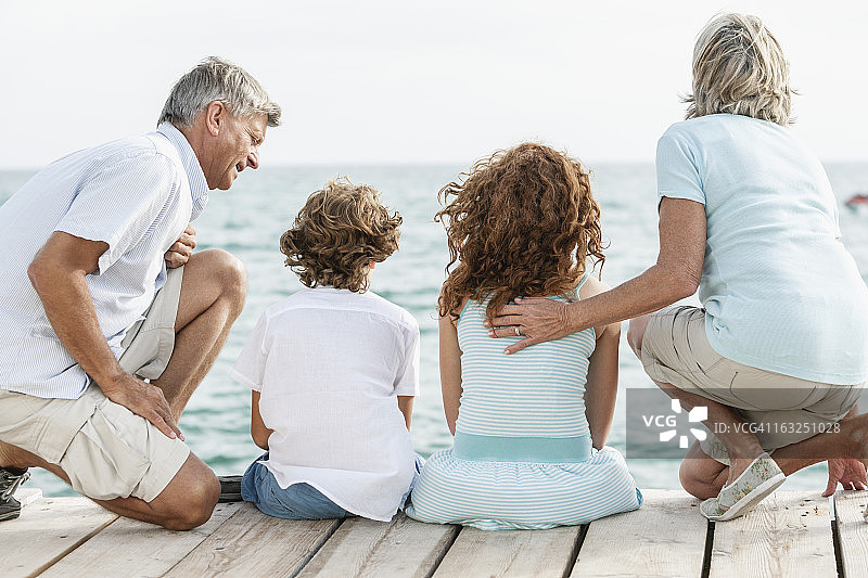西班牙，祖父母和孙子坐在码头上图片素材