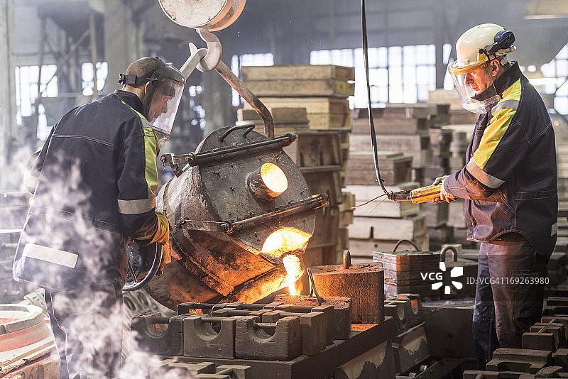 工人们将熔化的金属倒入铸造厂的模具中图片素材