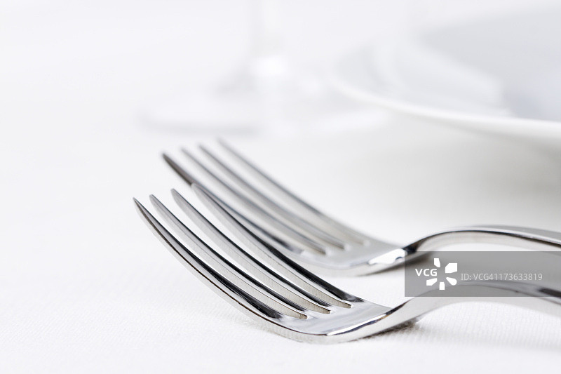 两个叉子，银器在白色的地方设置与盘子，玻璃图片素材