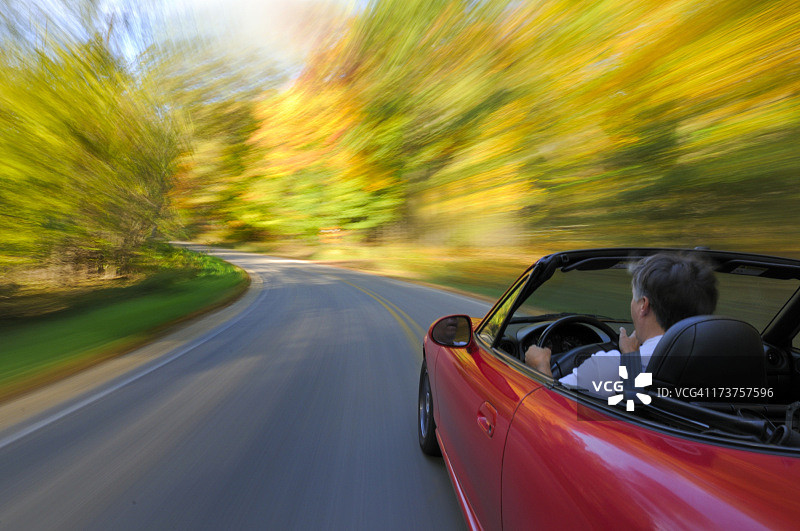 一辆红色的小轿车在秋风中疾驰图片素材