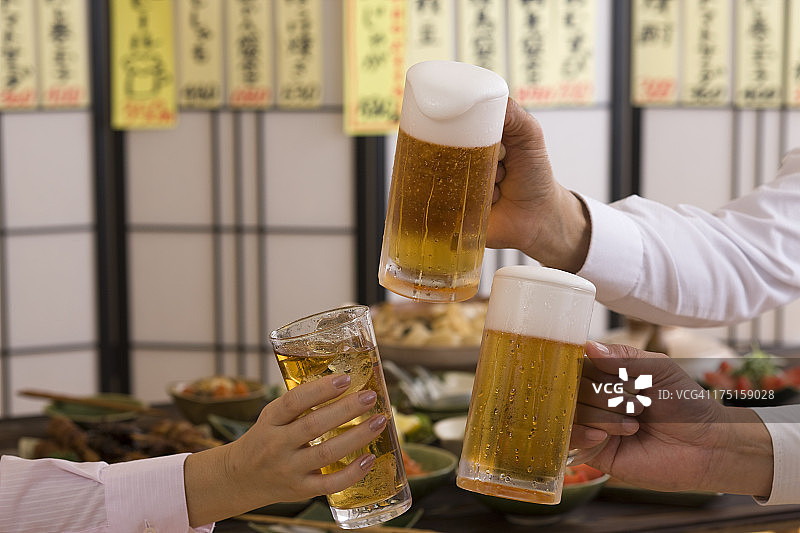 三个人在居酒屋用啤酒和Chu-Hi祝酒图片素材