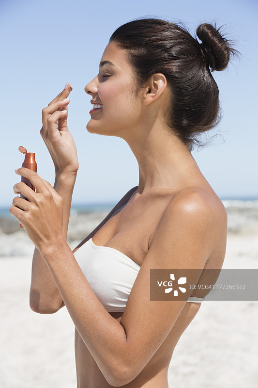 在海滩上闻着防晒油的漂亮女人图片素材