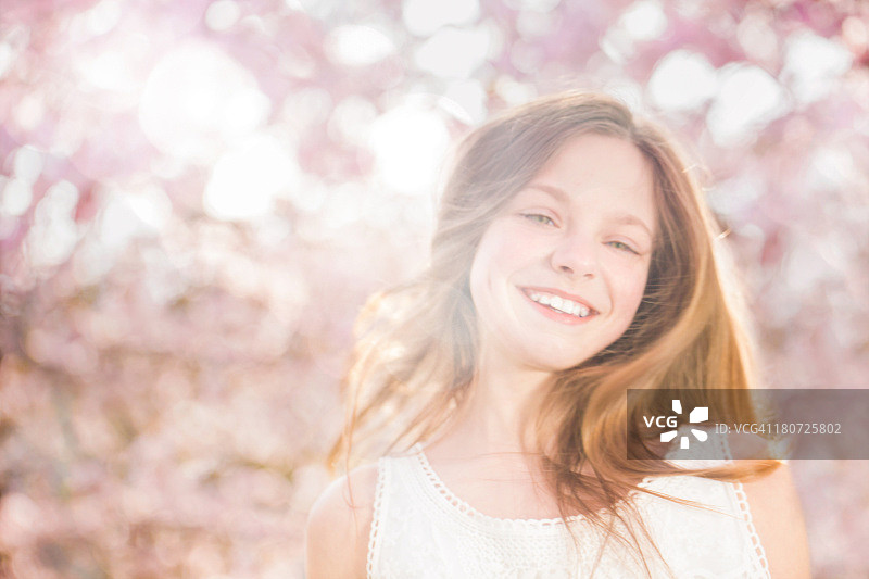 微笑的女孩看着相机在春天图片素材