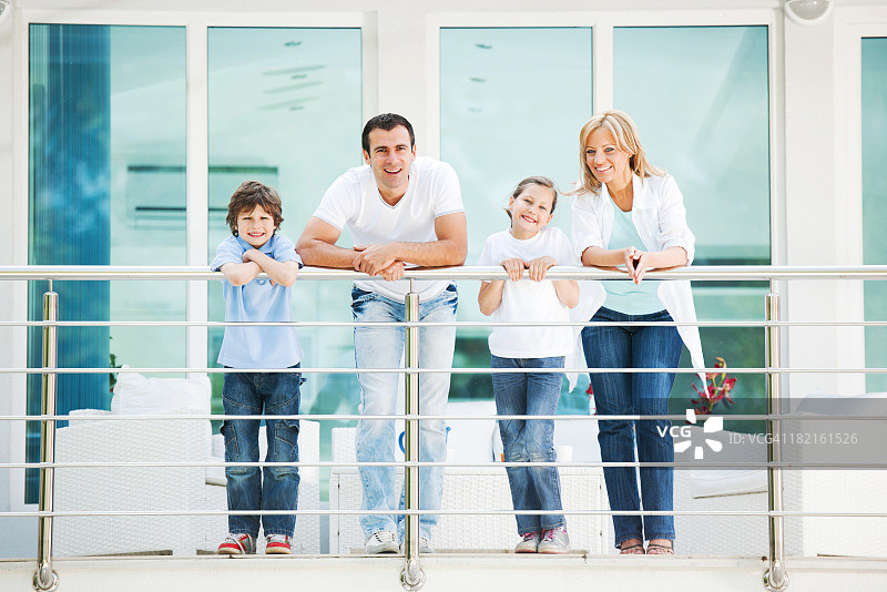 幸福的一家人站在阳台上。图片素材