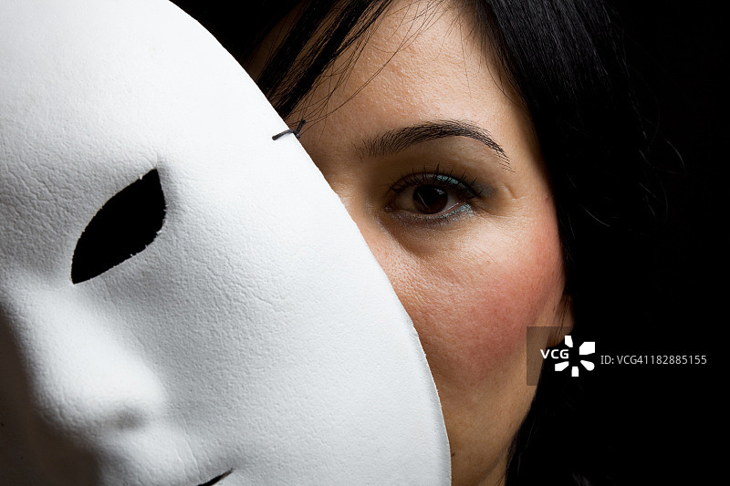 在白色面具后露出黑头发和眼睛的女人图片素材