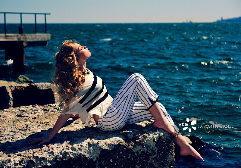 年轻女子坐在海边的石阶上图片素材