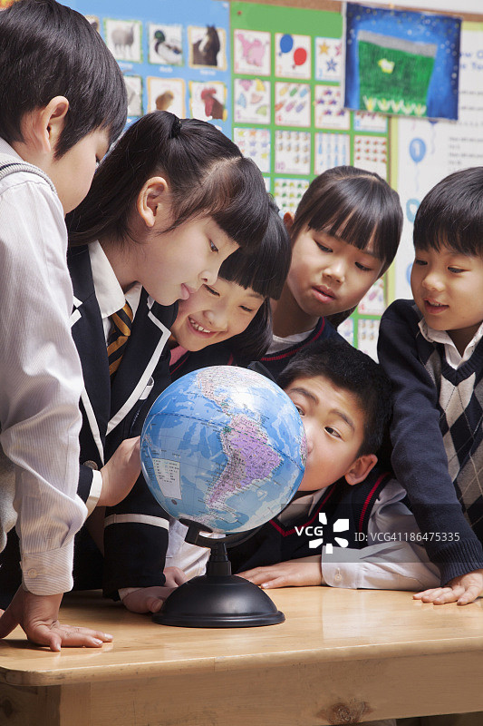 在教室里看地球仪的小学生图片素材