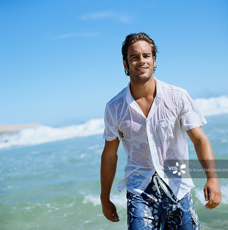 年轻人穿着湿衬衫在沙滩上散步，肖像图片素材