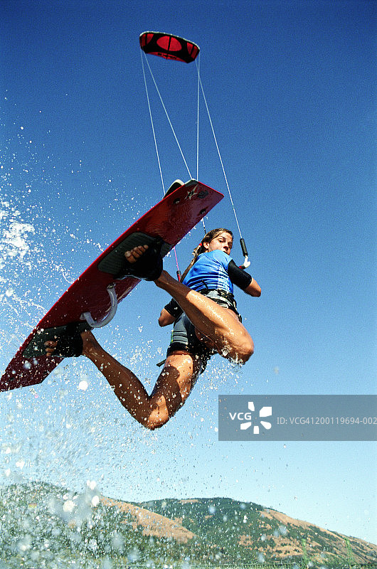女子风筝滑板在半空中，向后看，低角度视角图片素材