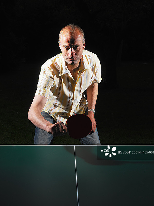 男人在乒乓球桌上拿着球拍，肖像图片素材
