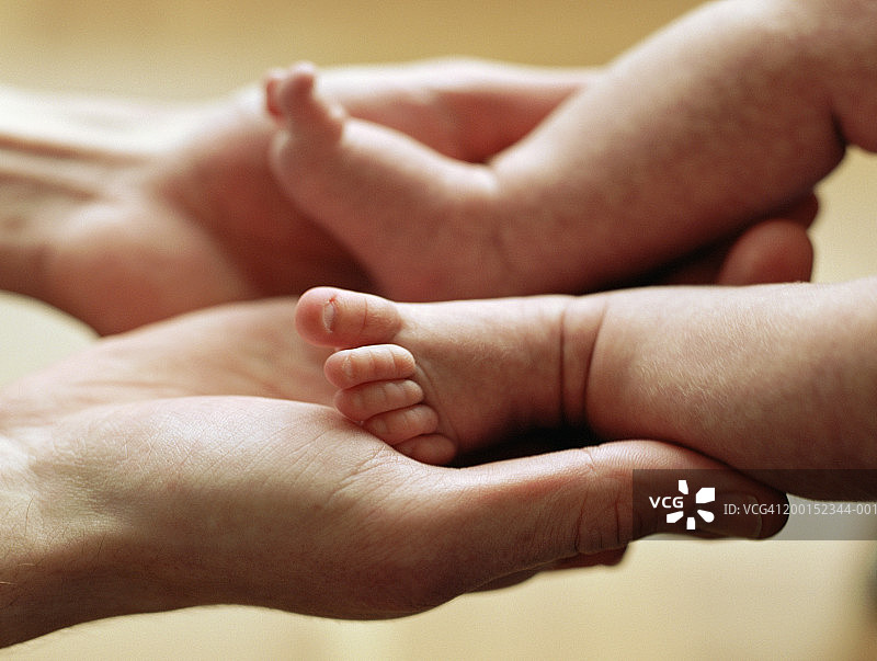 父亲抱着女婴的脚(6-9个月)，特写图片素材