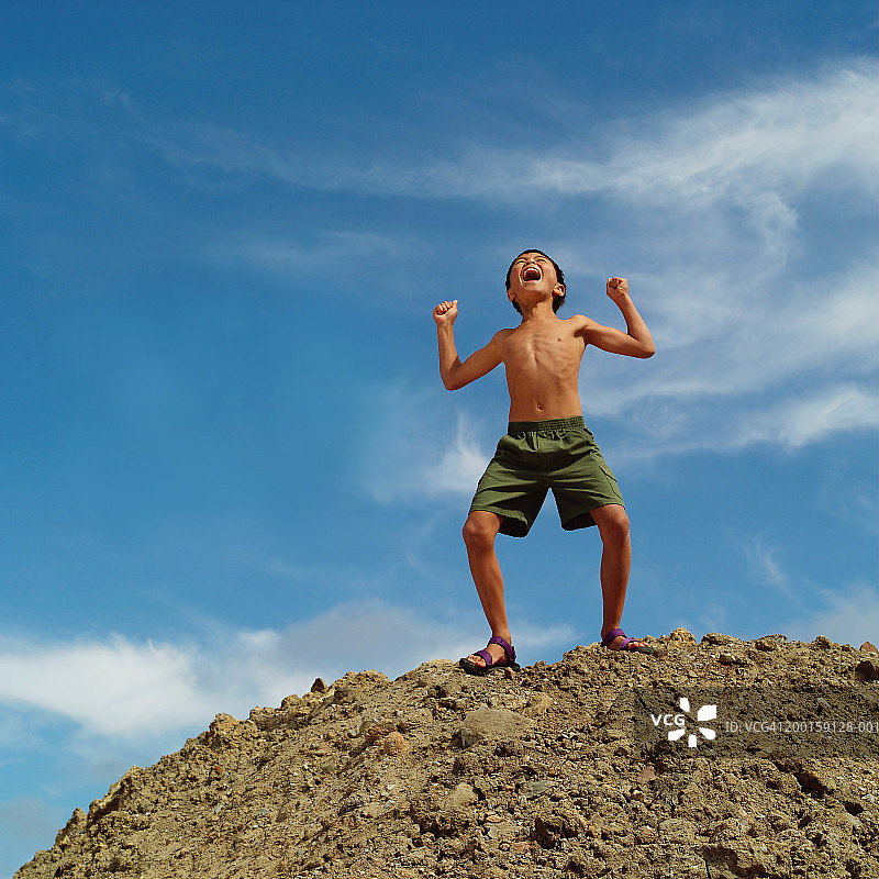 一个男孩(7-9)站在山顶，举起手臂大喊大叫图片素材
