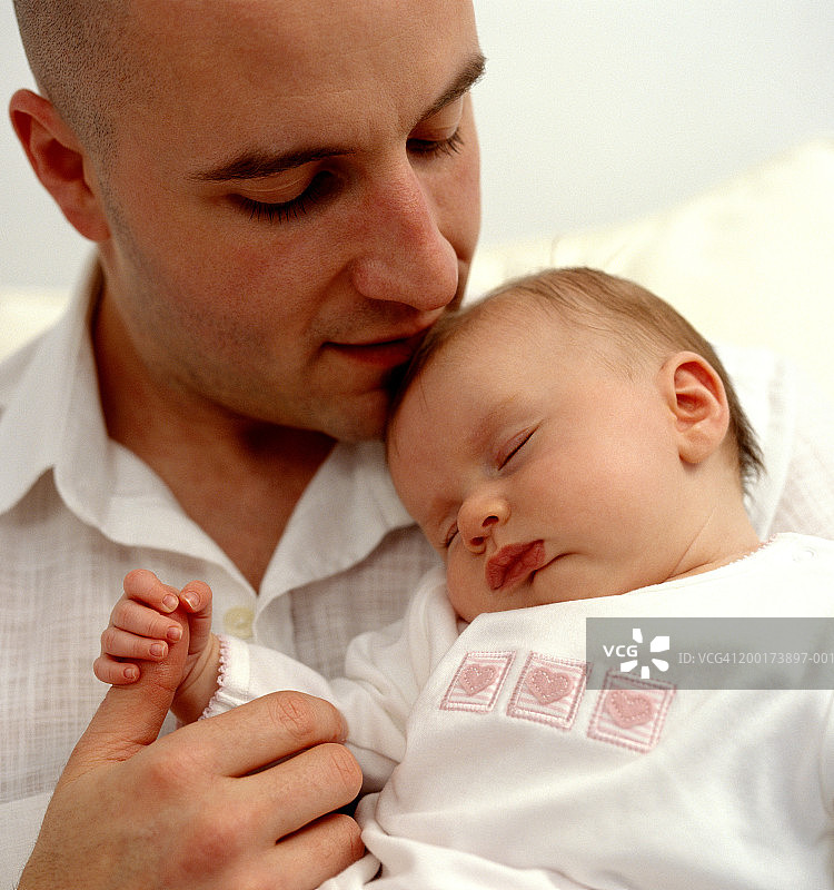 父亲拥抱熟睡中的女婴(0-3个月)，特写图片素材