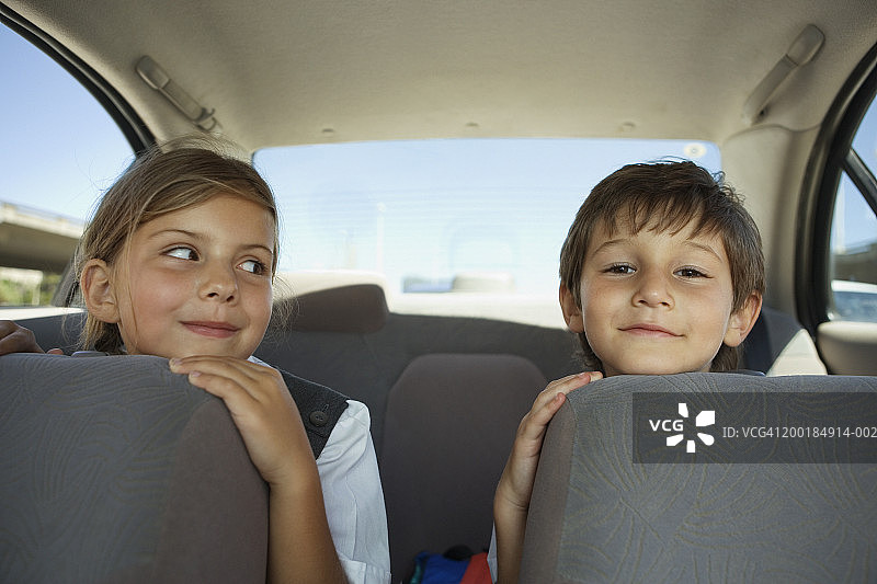 男孩和女孩(5-7岁)头靠在汽车座位上，面带微笑图片素材
