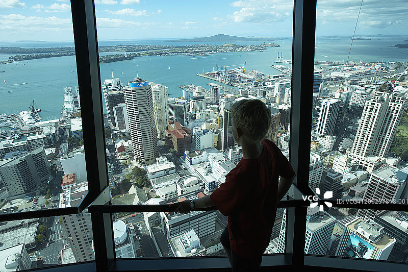 十几岁的男孩(12-14岁)在天空塔看城市景观，后视图图片素材