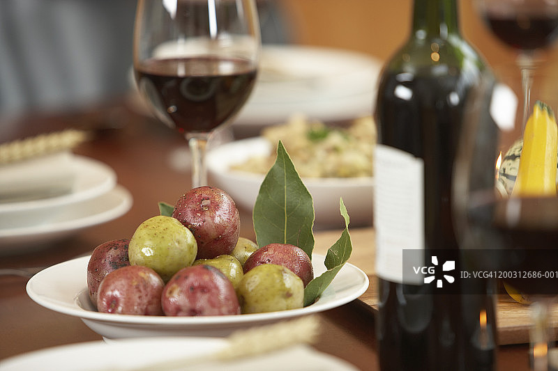 餐桌上的食物和红酒(重点放在前景的一碗土豆)图片素材