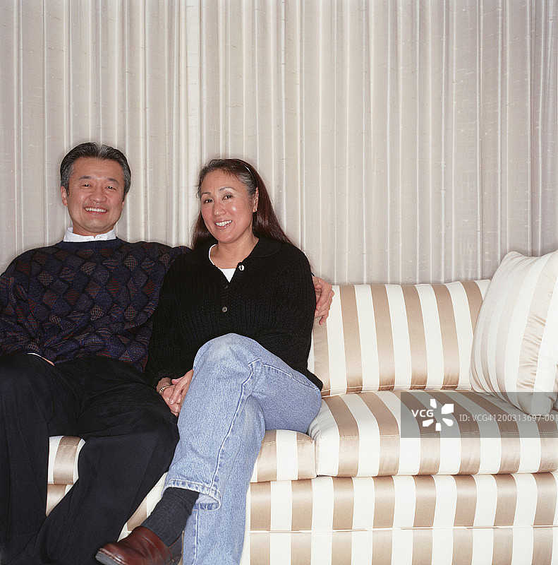 夫妇二人坐在客厅的沙发上，写真图片素材