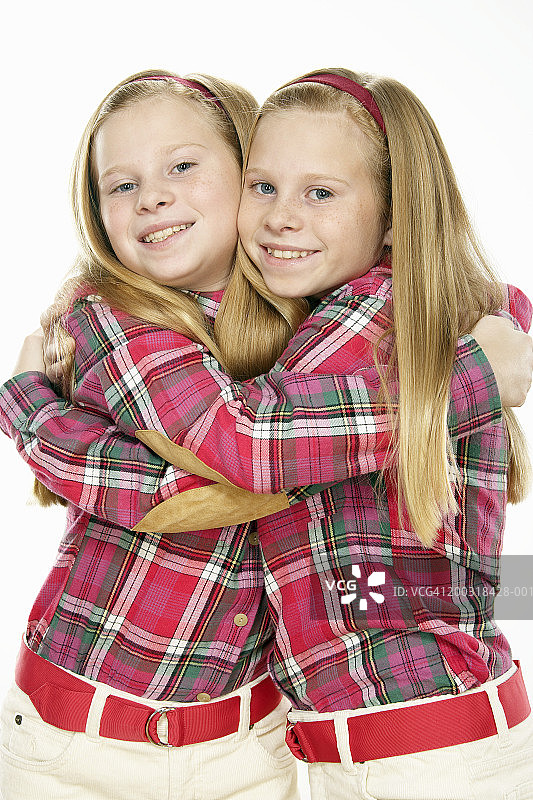 双胞胎女孩(10-12)拥抱，微笑，肖像图片素材