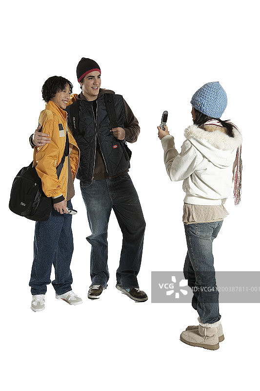 三个青少年(13-16岁)，女孩用手机给男孩拍照图片素材