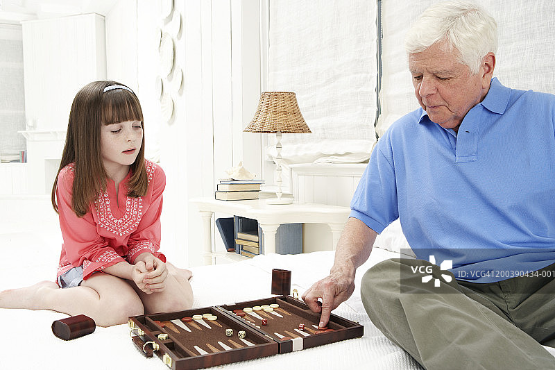 爷爷和孙女(8-10)在床上玩双陆棋图片素材