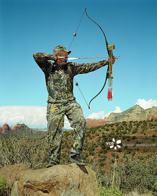 穿着迷彩服的人在沙漠中使用弓箭图片素材
