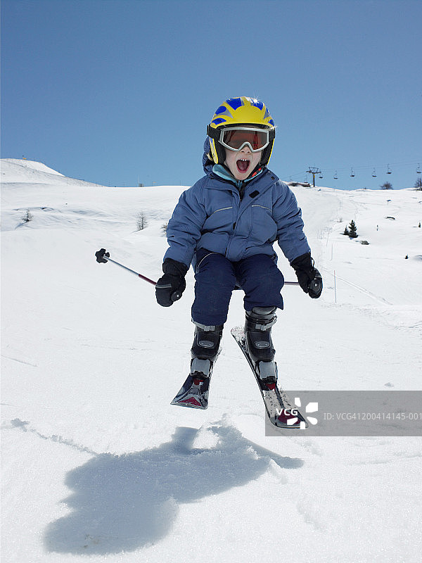 男孩(5-7)在白雪覆盖的斜坡上表演跳台滑雪，张着嘴图片素材